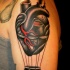 Tatuaje en el brazo, corazón humano negro con parte de globo