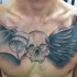 Tatuaje en el pecho,  cráneo humano con cuerno y alas de murciélago y cuervo