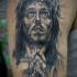 Tatuaje en el brazo, retrato de jesús triste que ora