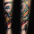 Watercolor style painted forearm tattoo of beautiful colored bird