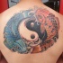 Tatuaje en la espalda, yin yang grande con dos peces azul y naranja