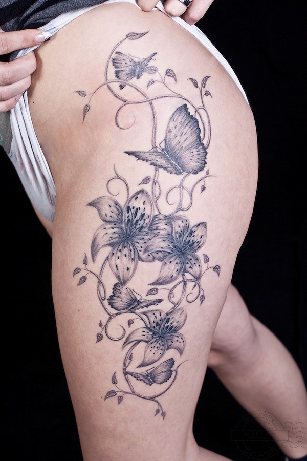 gigli tigre e farfalle tatuaggio sulla coscia femminile