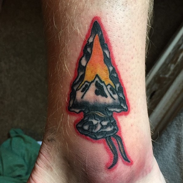 Tatuaje en el tobillo, punta de flecha decorada con montañas