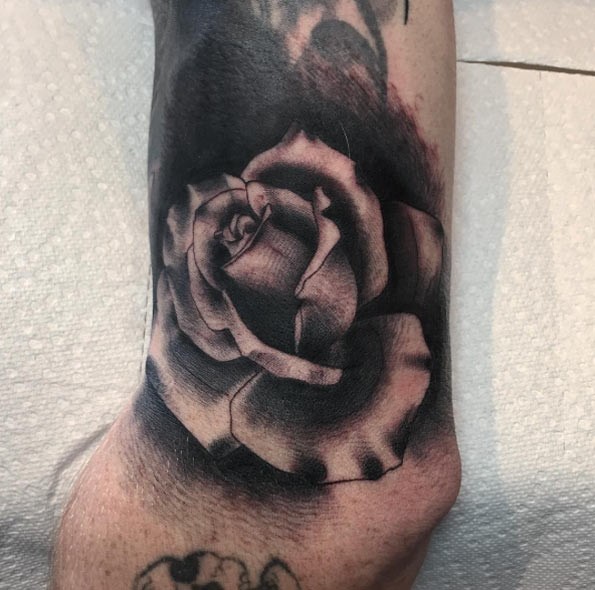 Tiny black and white detailed rose tattoo on wrist