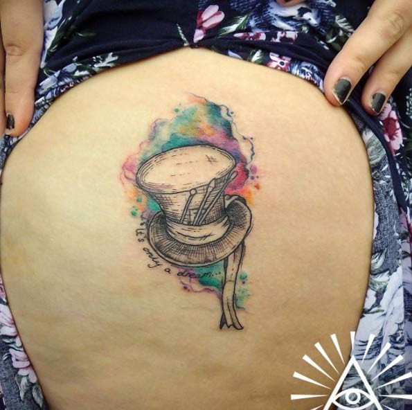 Tiny black and white fantasy hero hat tattoo on thigh with lettering