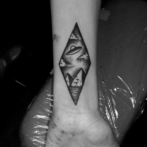 Tiny black ink alien ship with pyramids tattoo on wrist