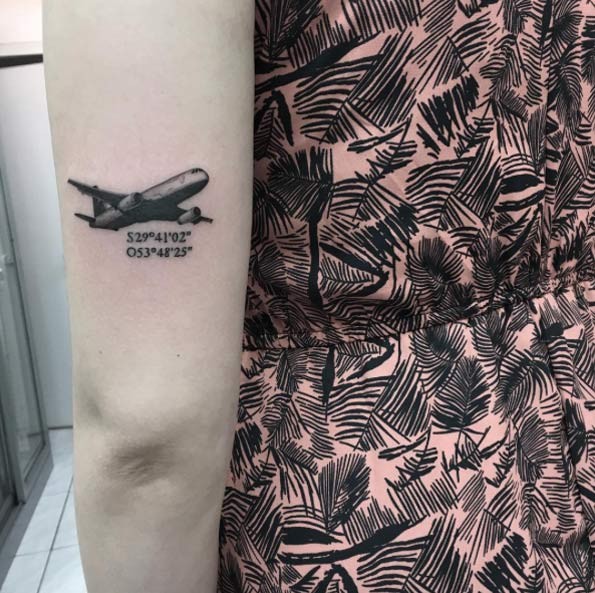 Tiny black ink arm tattoo of plane with coordinates