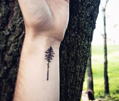 Tiny black ink tree tattoo on wrist