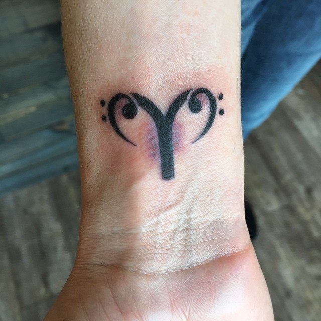 Tiny black ink wrist tattoo of Capricorn