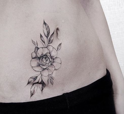 Tiny blackwork style belly tattoo of flower painted by Zihwa