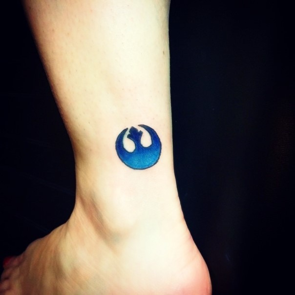 Tiny blue colored simple ankle tattoo of Rebel Alliance emblem