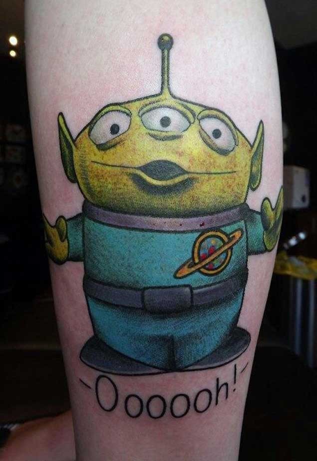 Tiny cartoon like colored little alien tattoo with lettering