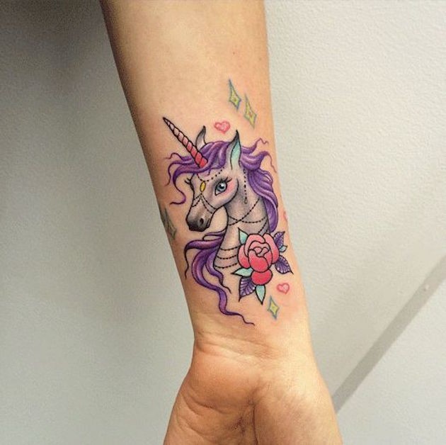 Tiny cartoon like colorful wrist tattoo of unicorn with rose
