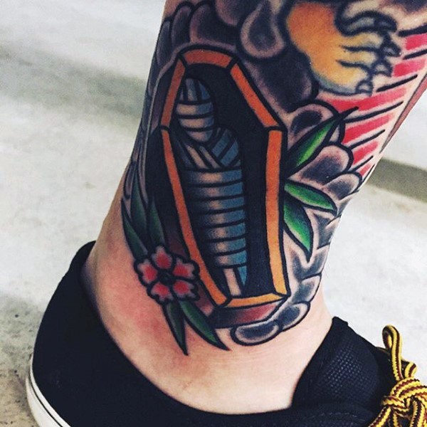 Tiny colored coffin with mummy and flowers tattoo on ankle
