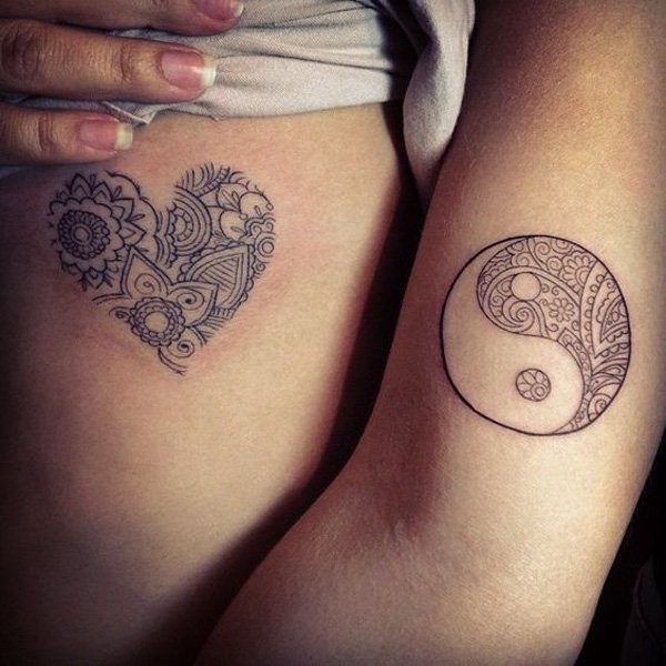 Winziges herzförmiges und Yin-Yang Symbolförmiges Tattoo an der Seite und Arm mit ornamentalen Blumen