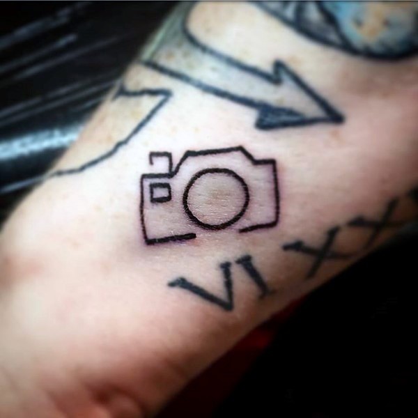 Winziges hausgemachtes schwarzes Tattoo mit Kamera am Arm