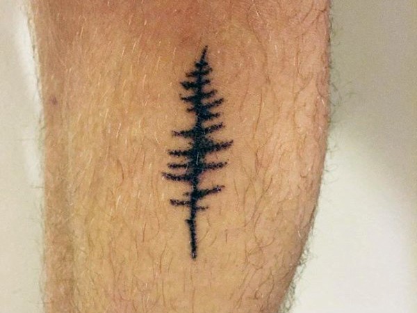 Kleines selbstgemachtes schwarzes Tattoo mit einsamem Baum am Bein