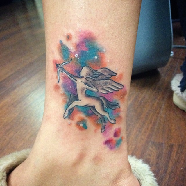 Tiny homemade like colored ankle tattoo of Sagittarius in space