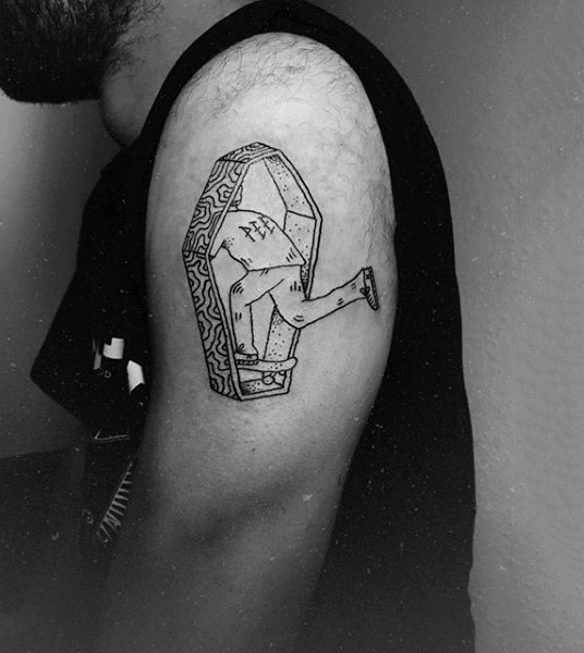 Tiny interesting looking coffin with skateboarder tattoo on shoulder stylized with lettering