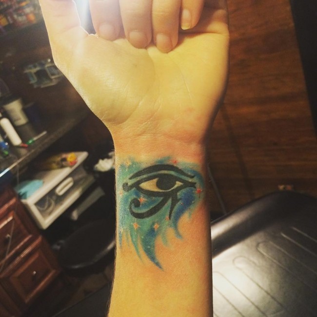 Tatuaje en la muñeca,
 ojo de Horus  negro en el fondo azul