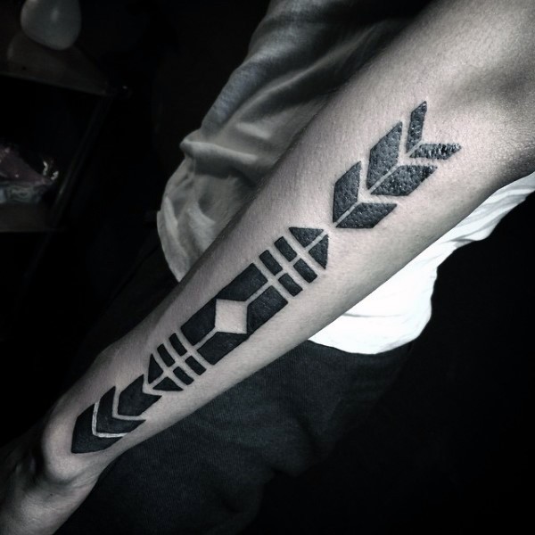 Tribal style black and white arrow shaped tattoo on forearm