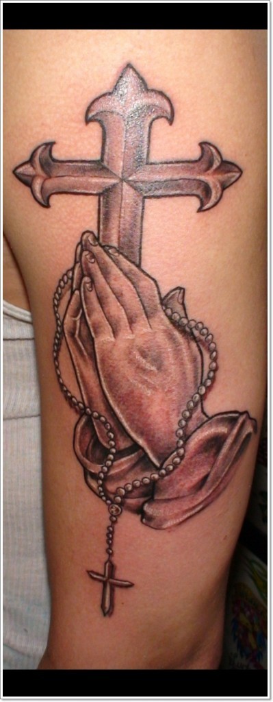 Typisches großes antikes Kreuz mit den betenden Händen Tattoo am Unterarm