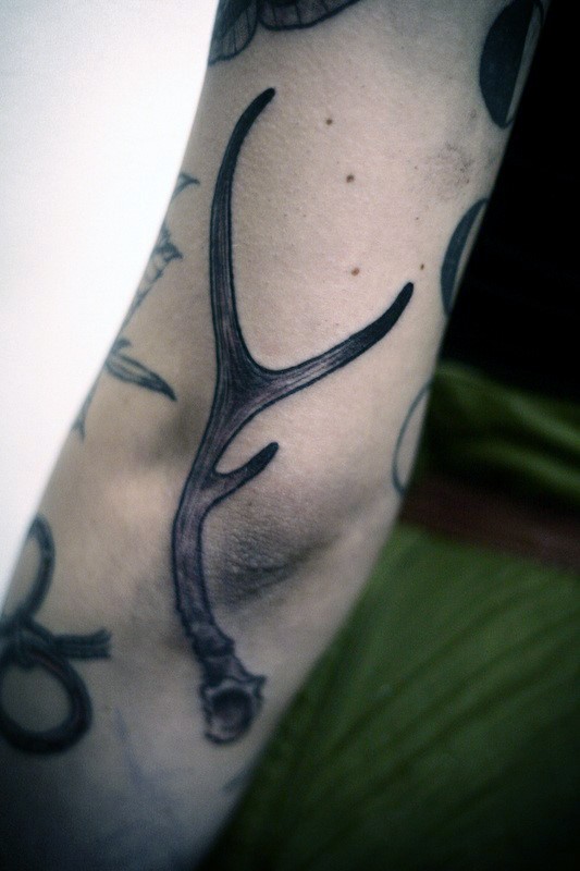 Typical black and gray style arm tattoo of deer horn