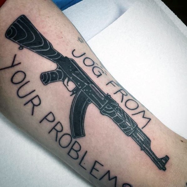 Typical black ink arm tattoo of AK rifle with lettering