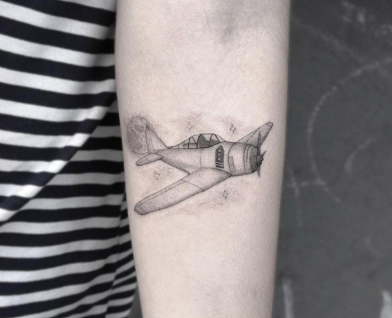 Typical black ink arm tattoo of flying plane with stars