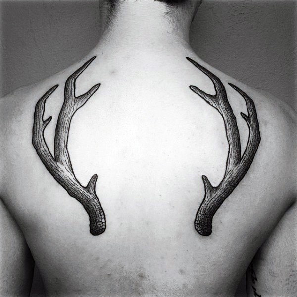 Typical black ink engraving style upper back tattoo of deer horns