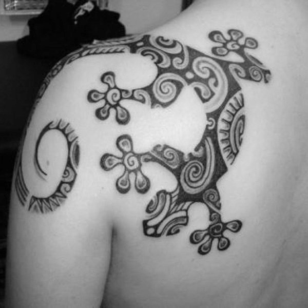 Typical black ink lizard tattoo on shoulder stylized with Polynesian ornaments