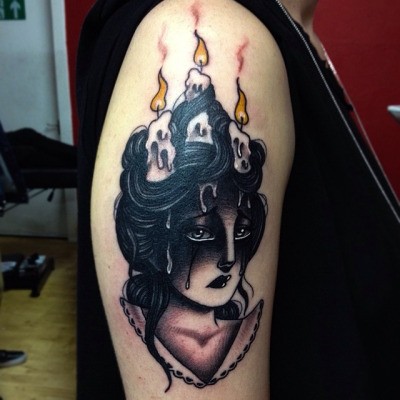 Typical colored shoulder tattoo of crying woman with burning candles in hair
