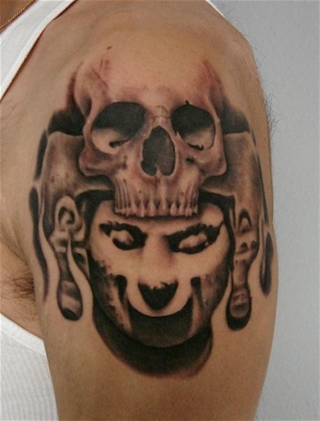 Typical colored shoulder tattoo of human skull and stone statue