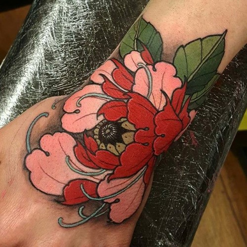 Typical new school style wrist tattoo of large flower with feather