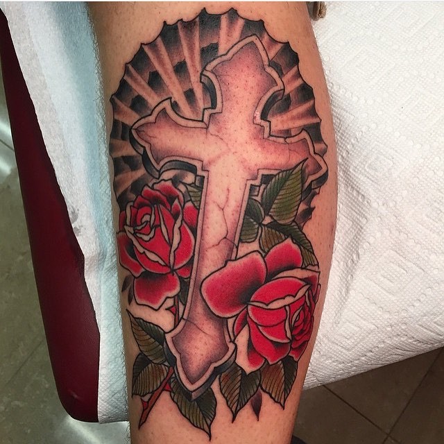 Typical old school style colored arm tattoo of stone cross with roses
