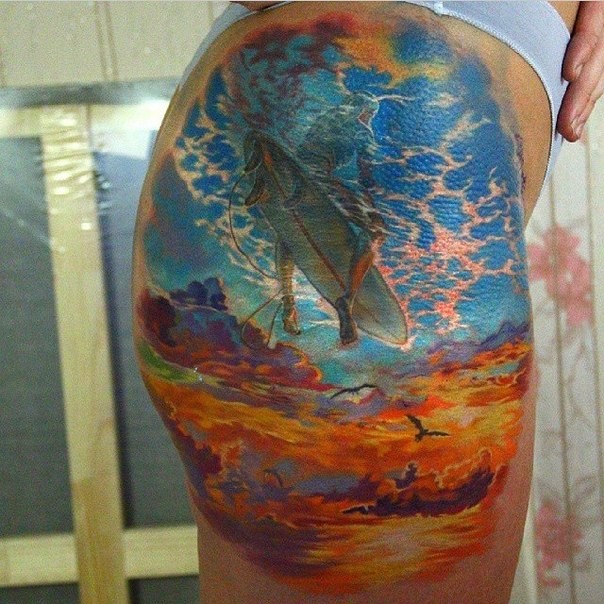 Unbelievable designed and colored thigh tattoo of surfer swimming the sky