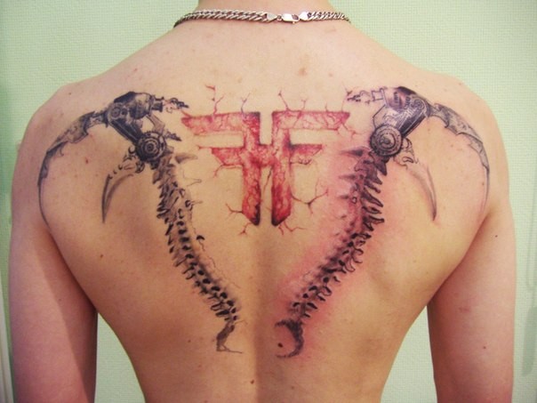 Unbelievable multicolored upper back tattoo of mystical symbol and bone like weapons