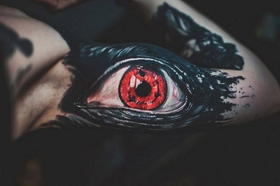 Uncanny great black eye with a red pupil tattoo on arm by Megan Allard