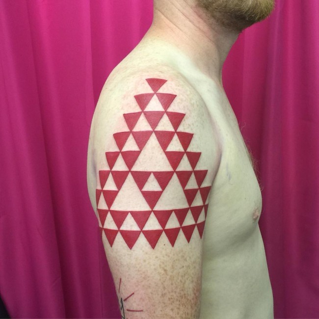 Unique big red colored symbol made from red triangles tattoo on shoulder