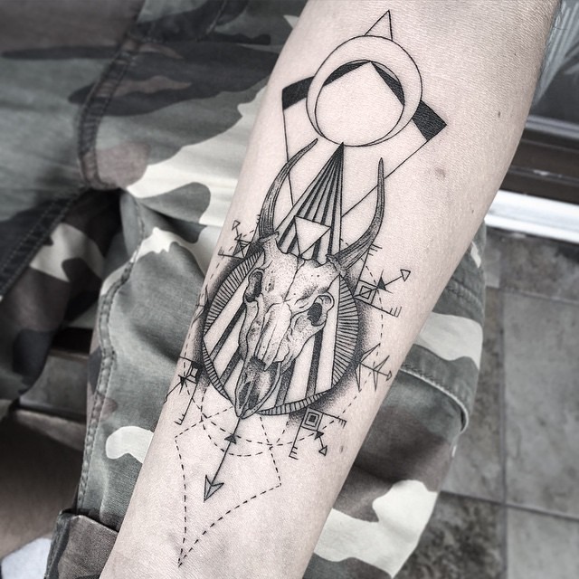 Unique black ink animal skull tattoo on forearm combined with various cult symbols