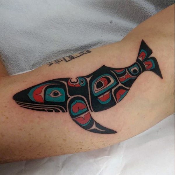 Unique designed and colored big whaled tattoo on arm stylized with tribal ornaments