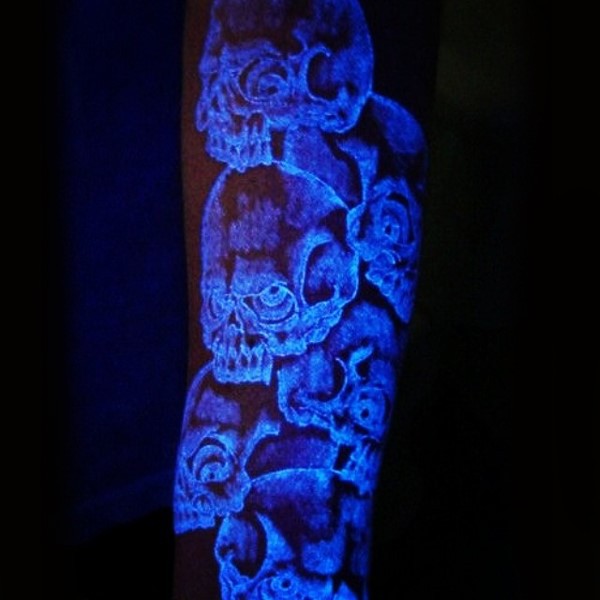 Unique designed glowing ink colored mad skulls tattoo on arm