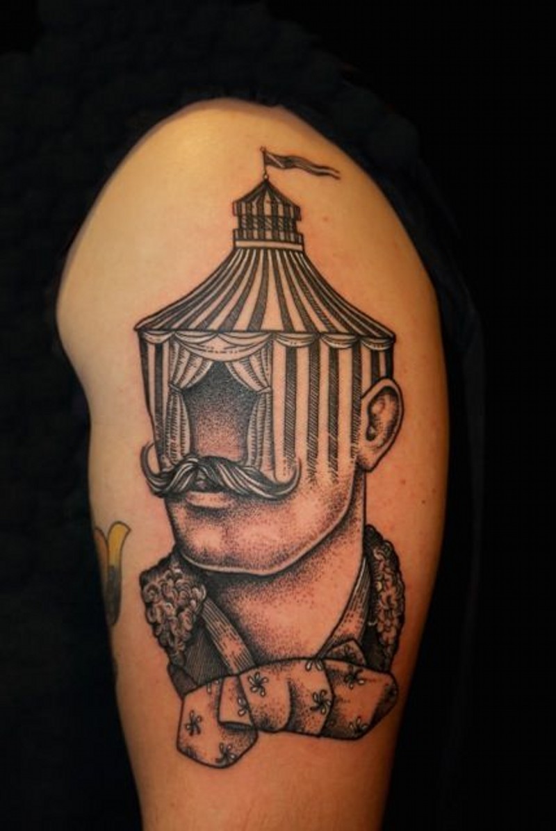 Tatuaje en el brazo, diseño de un hombre con bigotes con casa en lugar de cabeza