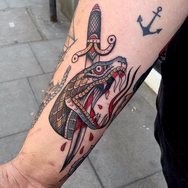 New school style colored arm tattoo of big bloody snake head with dagger