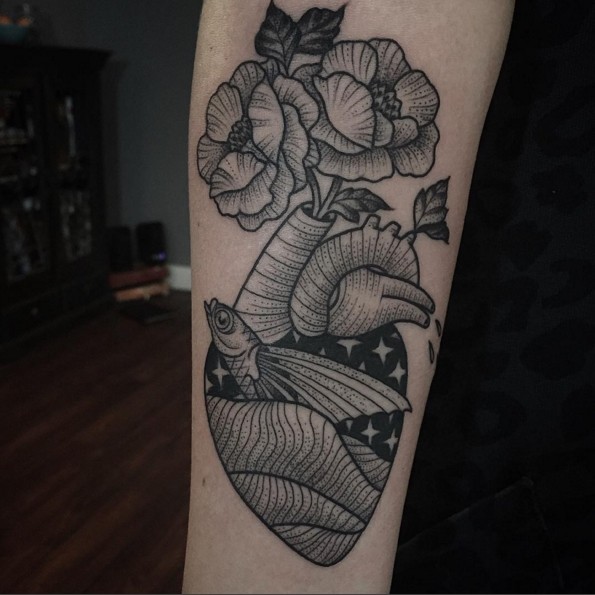 Unusual black ink old school style heart tattoo on forearm combined with fish and flowers