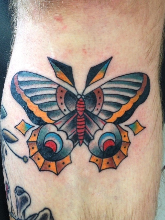 Unusual colored moth tattoo on mans leg