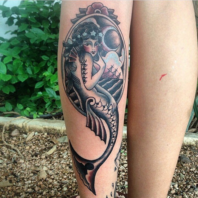 Unusual colored old school mermaid portrait tattoo on leg stylized with flower