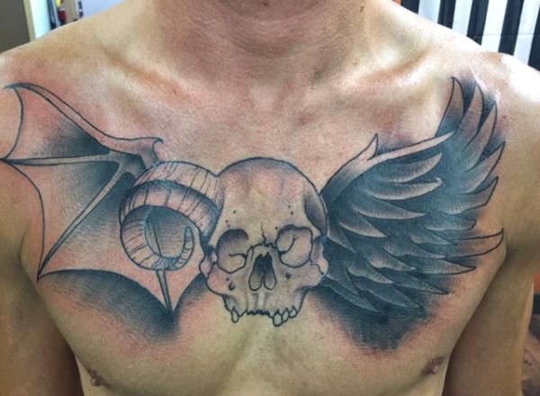 Tatuaje en el pecho,  cráneo humano con cuerno y alas de murciélago y cuervo