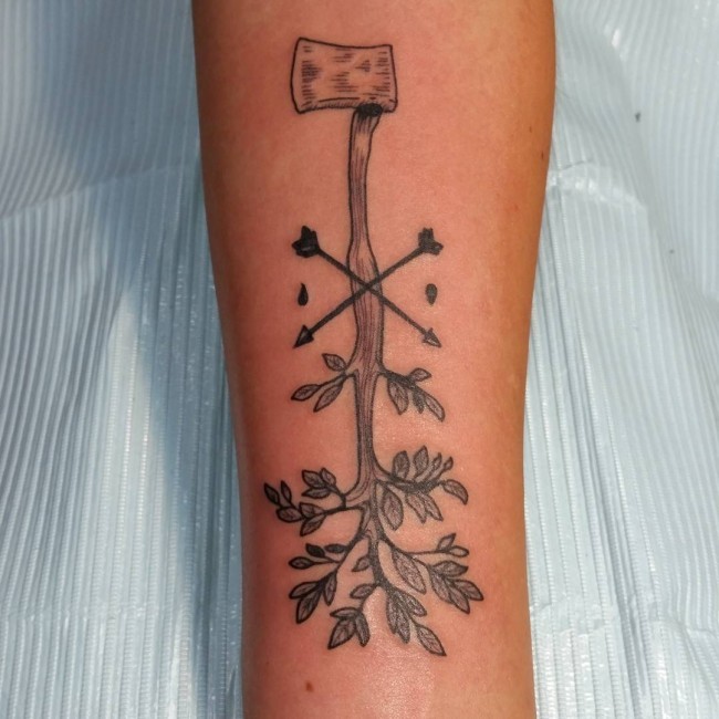 Unusual designed black ink axe tattoo on forearm with crossed arrow and leaves