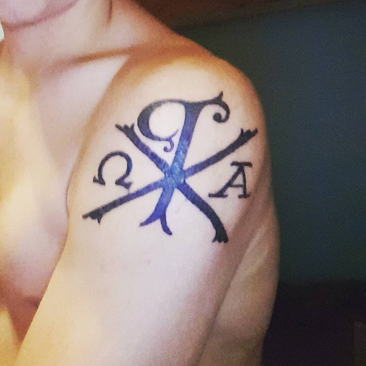 Upper arm tattoo of religious special symbol Chi Rho Christ monogram in dark black ink